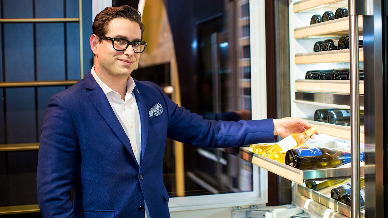 Portrait of Erik Segelbaum, next to a wine fridge.